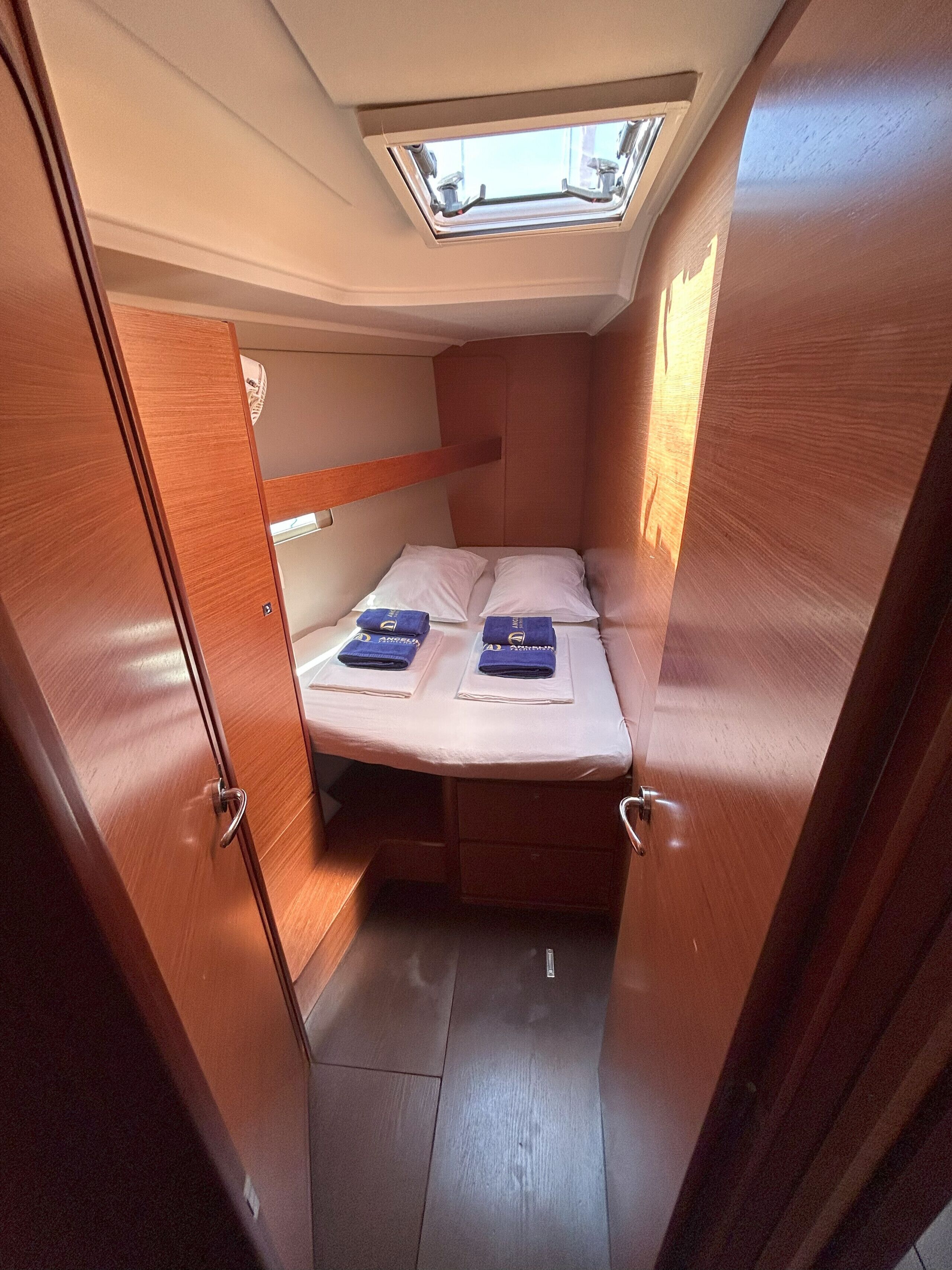 A compact cabin with a bunk bed, a skylight, and wooden walls.