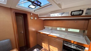 Eine kleine Kombühe mit Dachfenster, Holzschränken, Spüle und Herd.