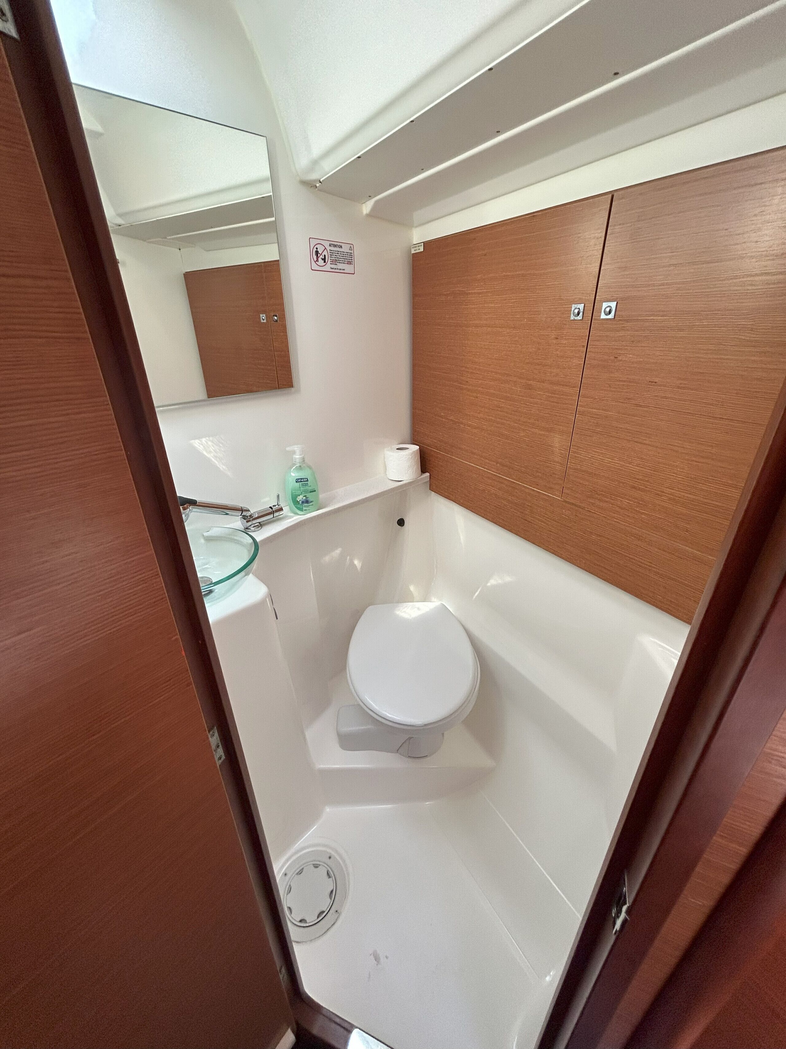 Un baño pequeño con inodoro, lavamanos y espejo.