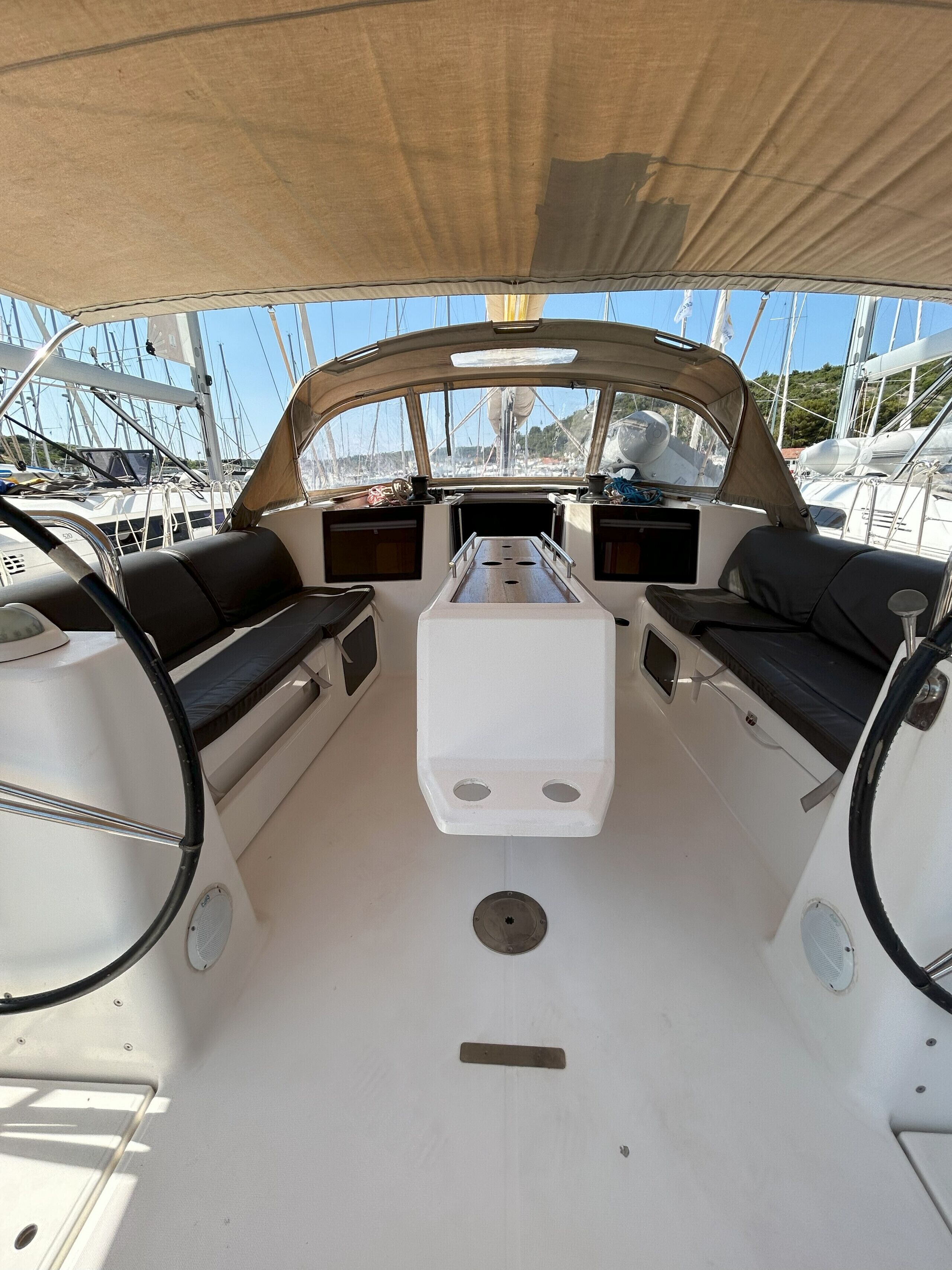 A boat deck with two seating areas, a central console, and a view of other boats in the marina.