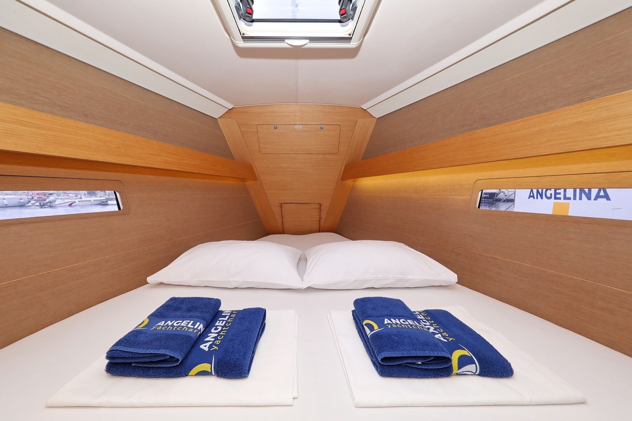 A cabin with two beds, each with a blue towel and a pillow, and a skylight above.