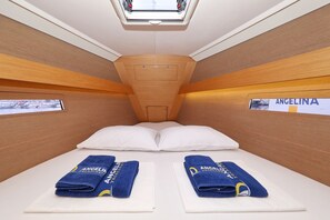 Une cabine équipée de deux lits, chacun avec une serviette bleue et un oreiller, et une lucarne au-dessus.