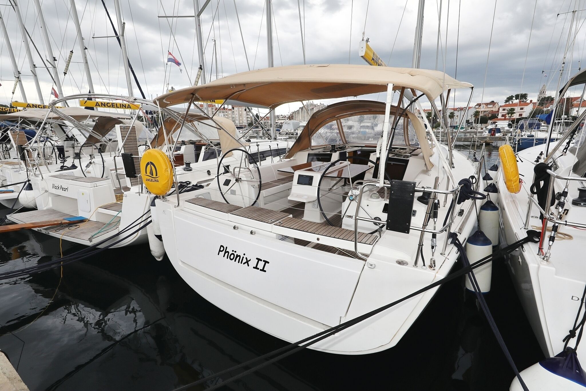 A marina with multiple sailboats docked, including one named 'Phönix II'.