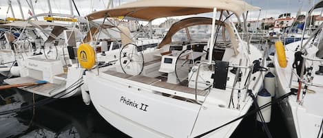 A marina with multiple sailboats docked, including one named 'Phönix II'.