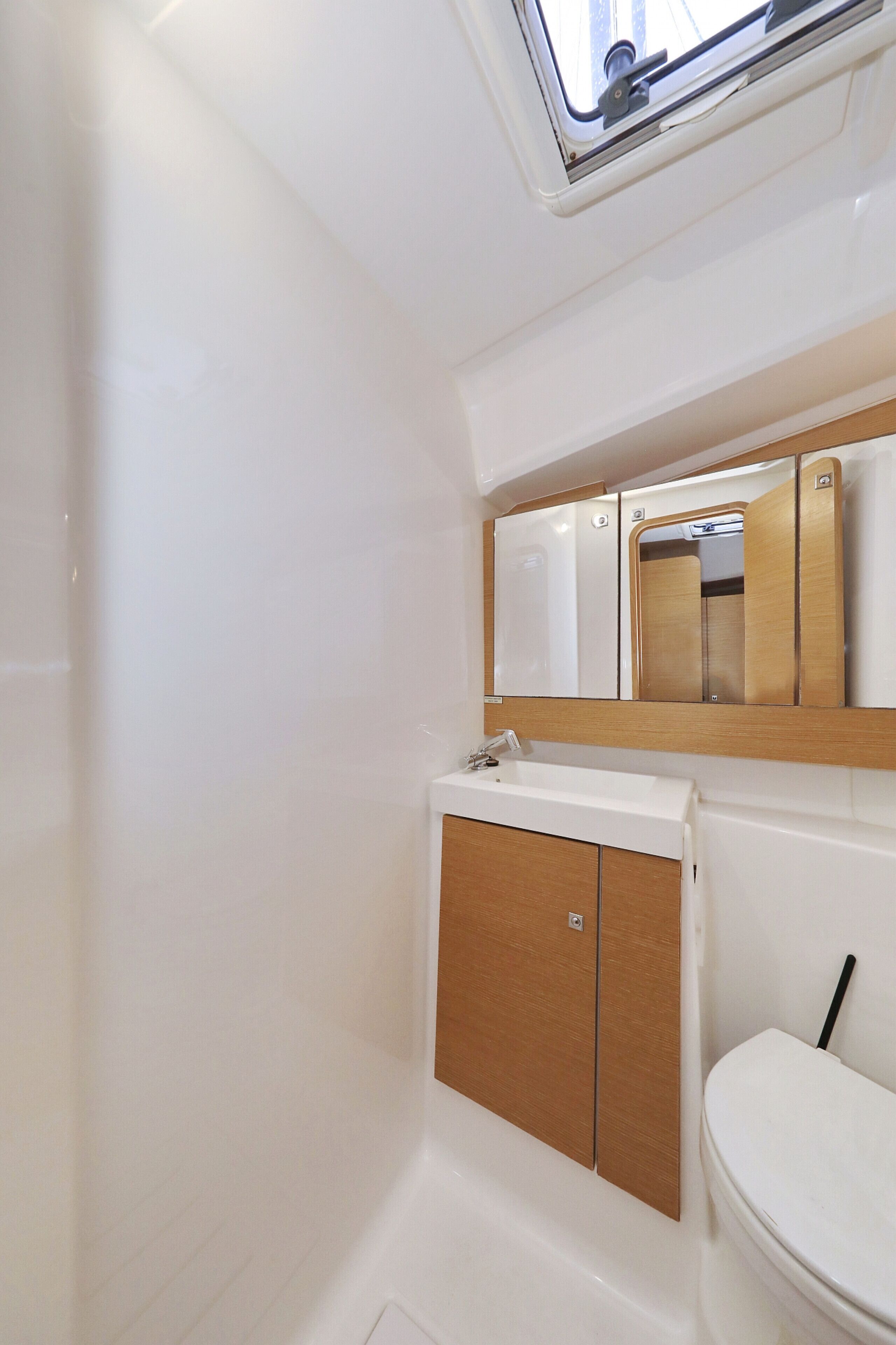 Un baño con lavamanos blanco, mueble de madera y un espejo encima.