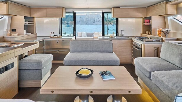 A modern interior with a kitchen, seating area, and large windows overlooking a body of water. - Sun-kissed Sailing Adventure in Split-Dalmatia, Croatia (Trogir)