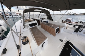 A boat deck with a wooden table, a white console, and a view of other boats and a marina. - Sun-Kissed Sailing Adventure in Northern Croatia (Punat)