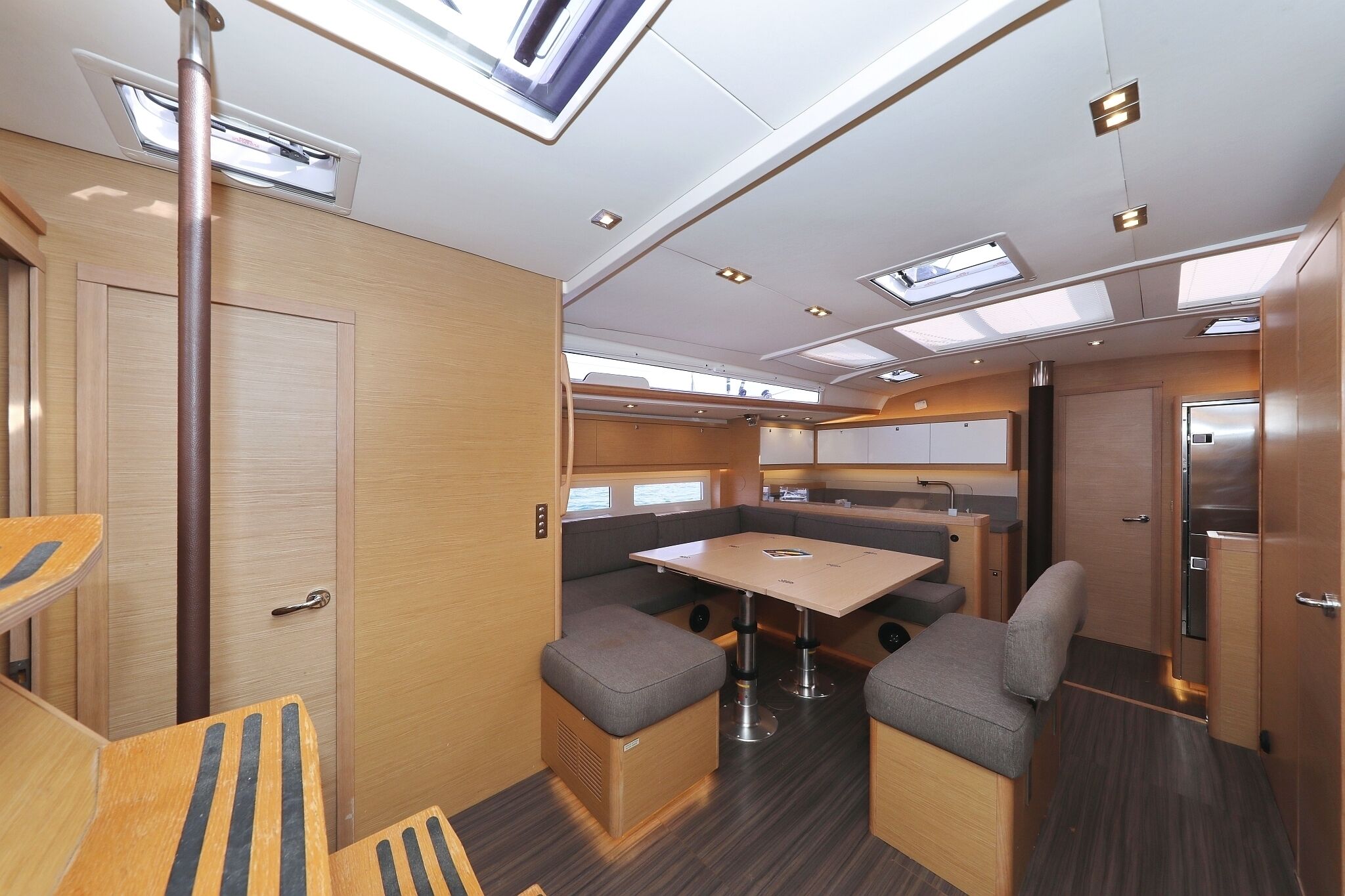 A compact RV interior with a kitchenette, a dining area, and a sleeping berth.