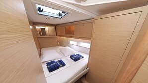 Una cabaña pequeña y luminosa con cama, armarios y un tragaluz.