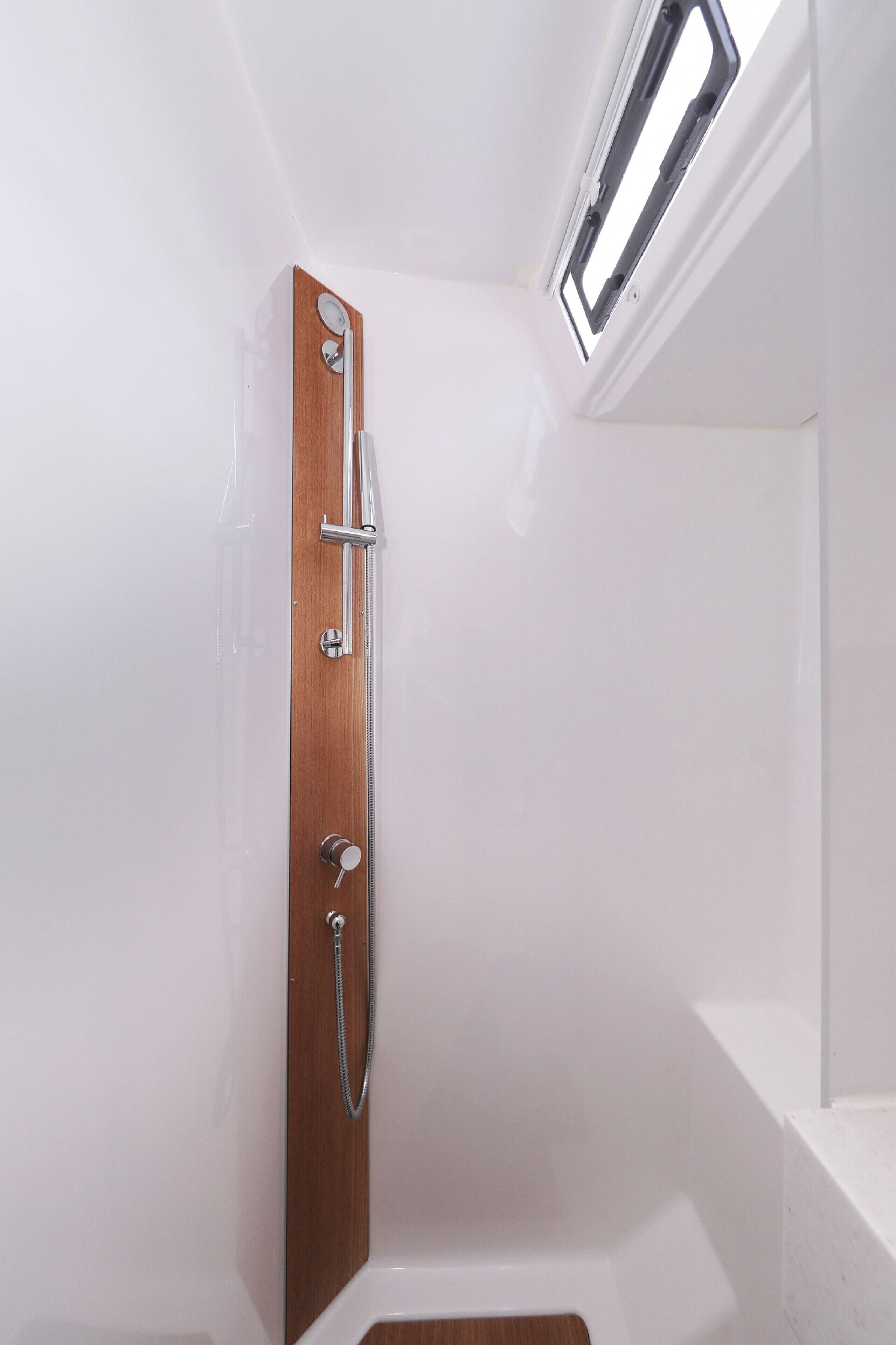 A shower with a wooden door, a glass enclosure, and a skylight.