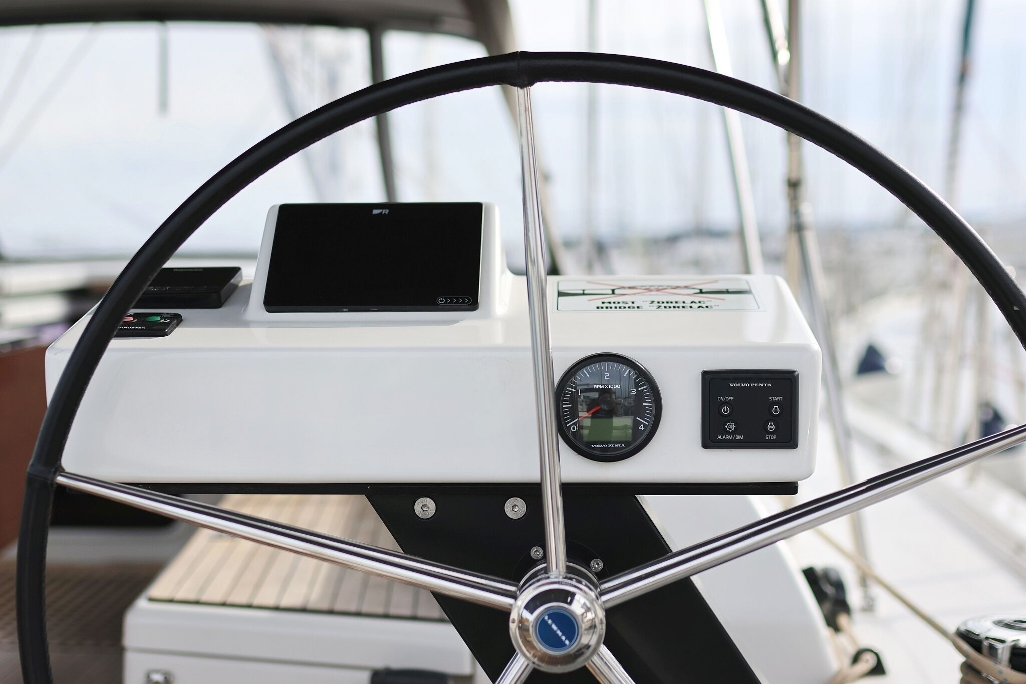 A boat's helm station with a steering wheel, control panel, and navigation screen.