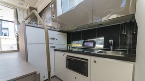 A compact kitchenette with a microwave, sink, and built-in oven. - Sun-Kissed Sailing Adventure in Zadar, Croatia (Bibinje)