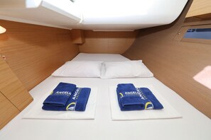 Une petite cabine équipée d’un lit, de deux serviettes et d’un intérieur en bois.