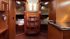 A compact interior with a central skylight, wooden paneling, a small kitchenette, and a bed. - Sun-Kissed Sailing Adventure in Zadar, Croatia (Bibinje)