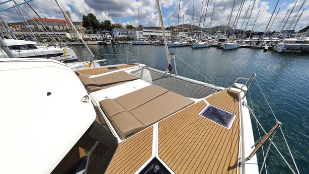 A marina with multiple boats docked, a wooden deck with seating, and a building in the background. - Sun-kissed Sailing Adventure in Split-Dalmatia, Croatia (Trogir)