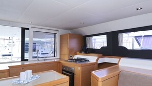 A compact kitchen with a gas stove, a sink, and a window overlooking a marina. - Sun-kissed Sailing Adventure in Split-Dalmatia, Croatia (Trogir)
