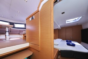 Espaço interior compacto e bem iluminado, com cama, área de estar e uma pequena cozinha.
