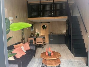 Um interior moderno com sofá, mesa de jantar, cozinha e escada.