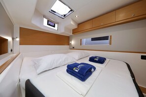 A bedroom with a skylight, a bed with white linens, a wooden headboard, and a small window. - Sibenik Sun and Beach Sailing Extravaganza: A Croatian Coastal Adventure (Vodice)