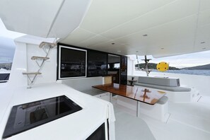 A boat's deck with a table, a window, and a yellow object. - Sibenik Sun and Beach Sailing Extravaganza: A Croatian Coastal Adventure (Vodice)