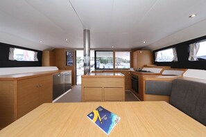 A modern kitchen with wooden cabinets, a central island, and a view of boats through large windows. - Sibenik Sun and Beach Sailing Extravaganza: A Croatian Coastal Adventure (Vodice)