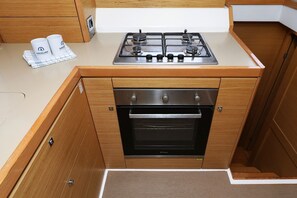 A compact kitchen with a gas stove, oven, and wooden cabinetry. - Sibenik Sun and Beach Sailing Extravaganza: A Croatian Coastal Adventure (Vodice)