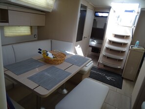 Una kitchenette compacta con una mesa, dos sillas, una cesta con botellas y un refrigerador pequeño.