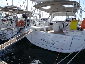 A white yacht named 'Gwennili' docked at a marina with a covered deck, life preserver, and a Yamaha outboard motor. - Sun-Kissed Sailing Adventure in Islas Sarónicas (Alimos)