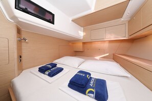 A compact, well-lit cabin with a bed, pillows, and neatly folded towels. - Sun-Kissed Sailing Adventure in Zadar, Croatia (Biograd na moru)