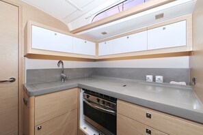 A compact kitchen with a built-in oven, a sink, and wooden cabinetry. - Sun-Kissed Sailing Adventure in Zadar, Croatia (Biograd na moru)