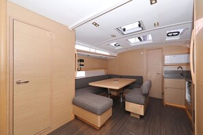 A compact RV interior with a kitchenette, a dining area with a table and cushioned seating, and a door. - Sun-Kissed Sailing Adventure in Zadar, Croatia (Biograd na moru)