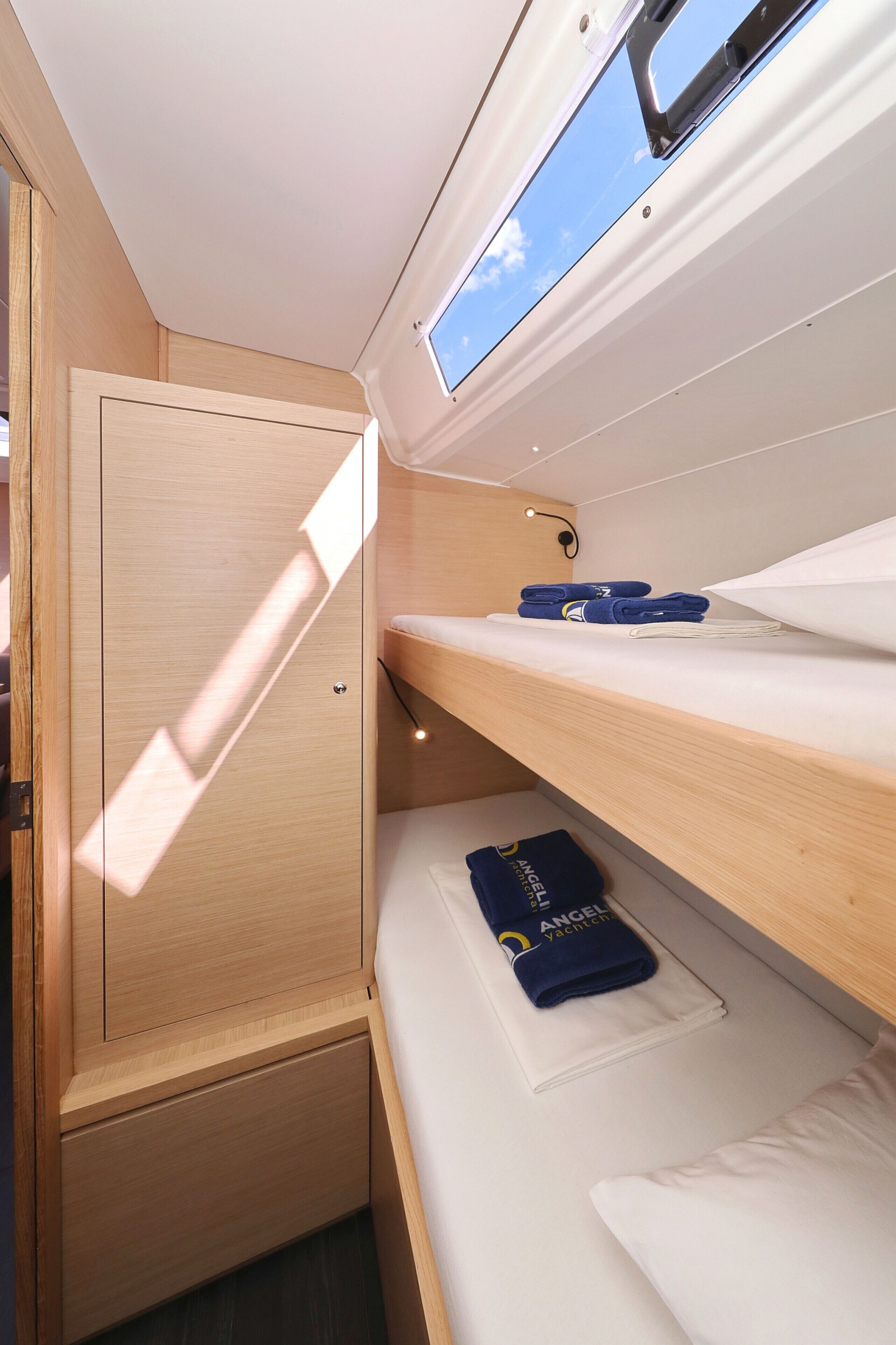 Une petite cabine équipée d’un lit superposé, d’une petite fenêtre et d’une armoire en bois.