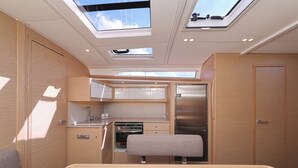Una kitchenette compacta con estufa, pileta y refrigerador, un pequeño banco y un tragaluz.