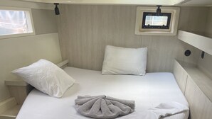 A compact bed with a headboard, a bedside table, and a small window.