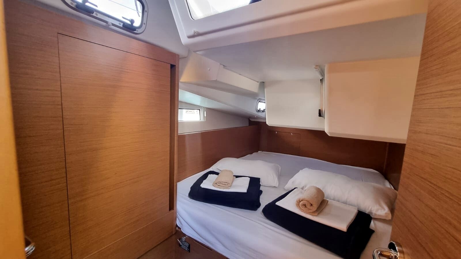 A compact, well-lit cabin with a single bed, a wardrobe, and a skylight.