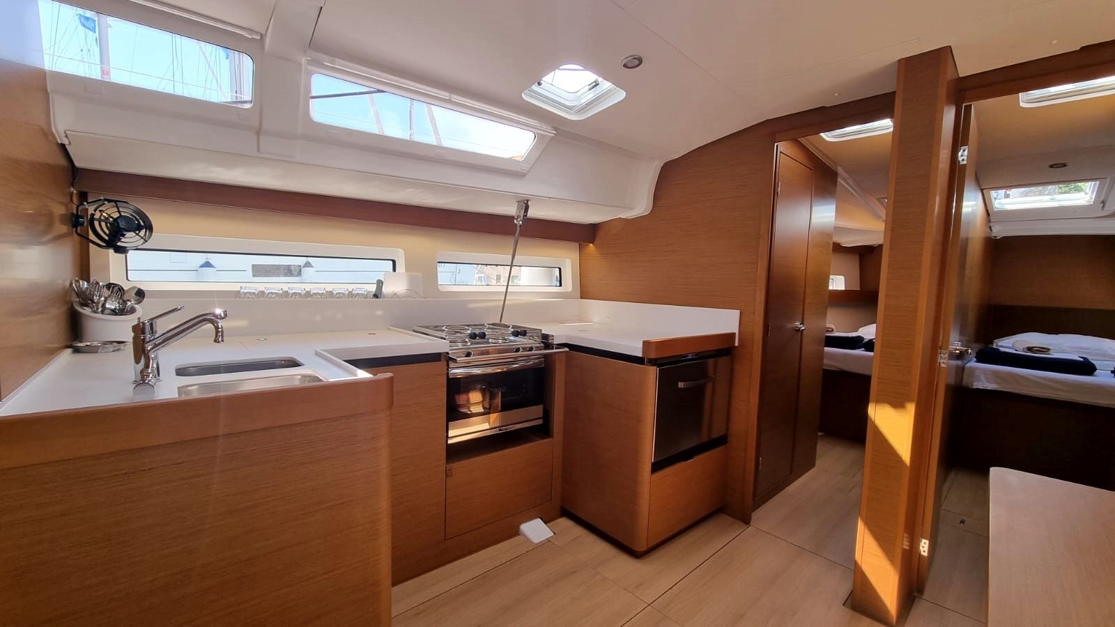 Une cuisine compacte équipée d’un évier, d’une cuisinière et d’un four, de meubles de rangement en bois et de fenêtres de toit.