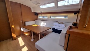 A compact boat interior with a table, cushioned seating, and a small window. - Sun-Kissed Sailing Adventure in Split, Croatia (Rogac)
