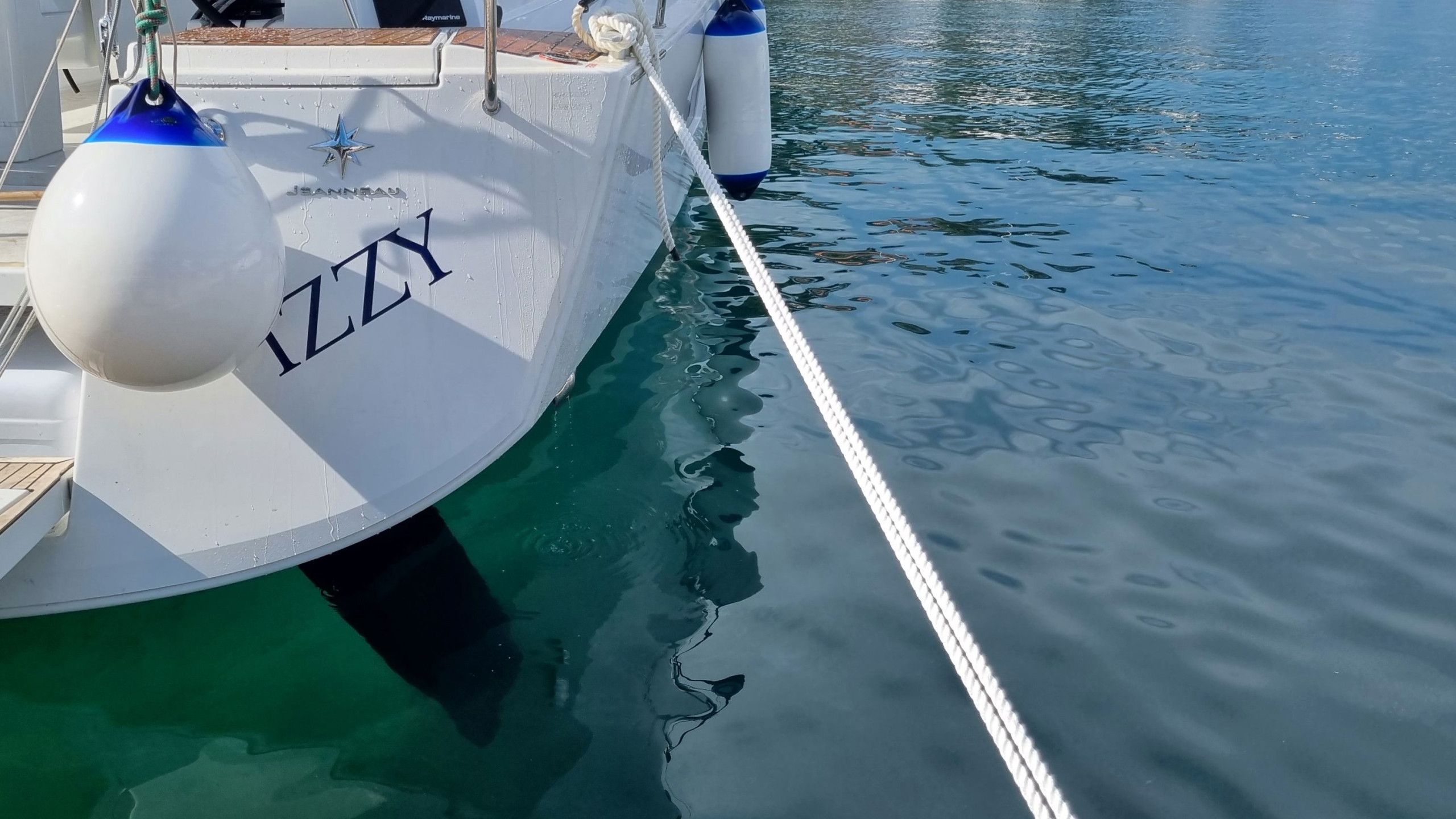 A boat docked at a marina with a rope tied to a buoy marked 'ZZ'.