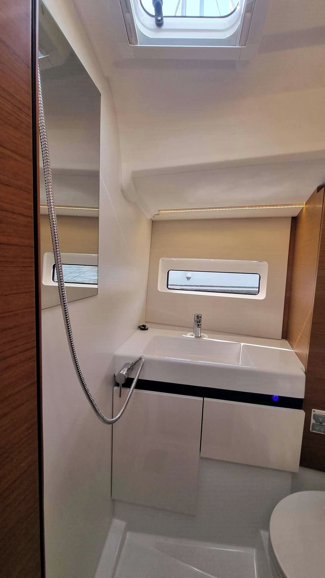 Une salle de bain moderne et compacte, dotée d’un puits de lumière, d’un lavabo intégré et d’une douche.