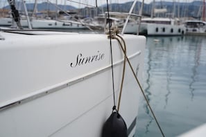 A white boat with the name 'Sunrise' on its side, docked at a marina with other boats in the background. - Sun-Kissed Sailing Adventure in the Ionian Islands, Lefkada (Lefkada)