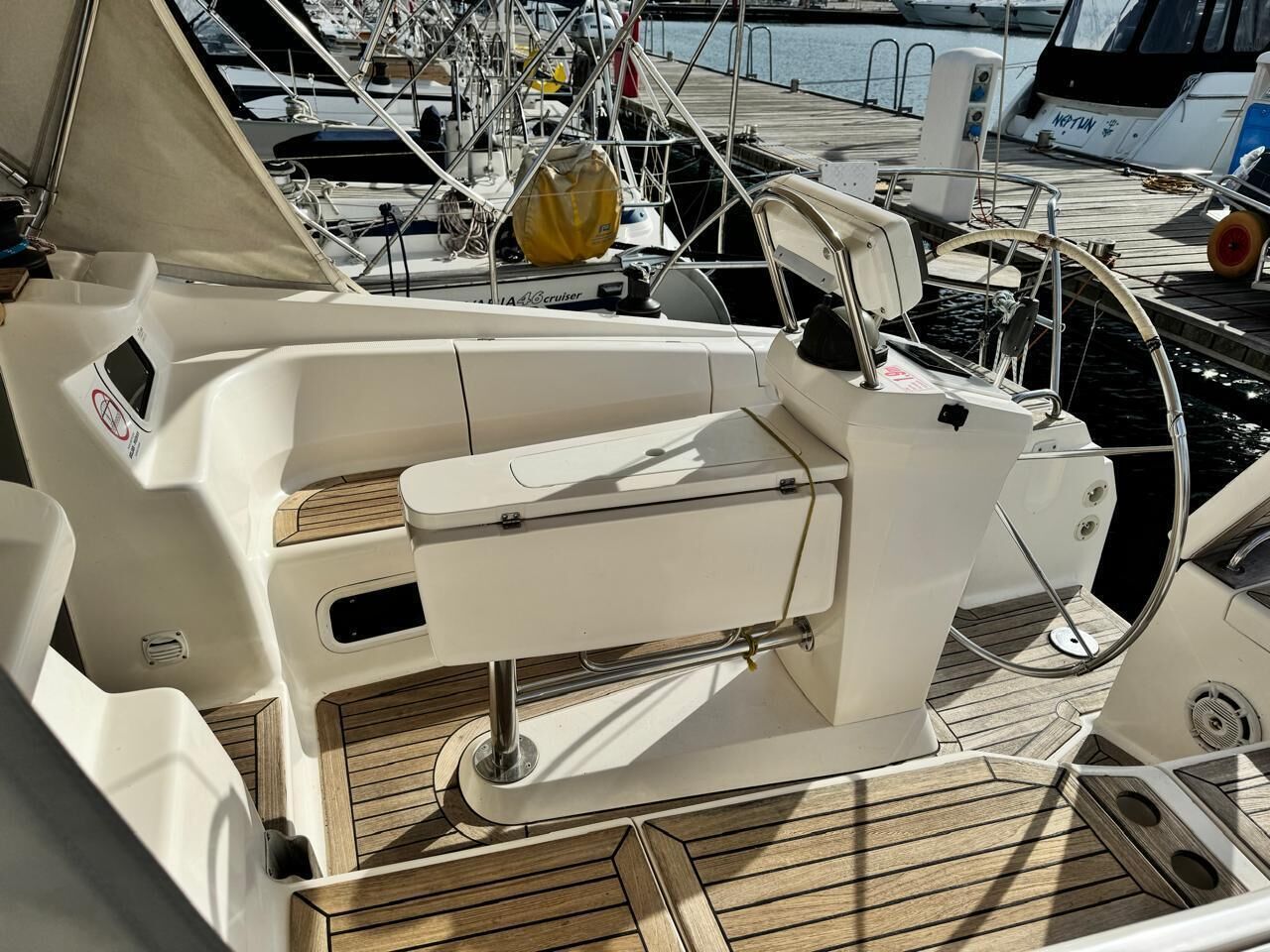 Ein Bootsdeck mit gepolsterten Sitzgelegenheiten, einem Steuer und einer Bedieneinheit.