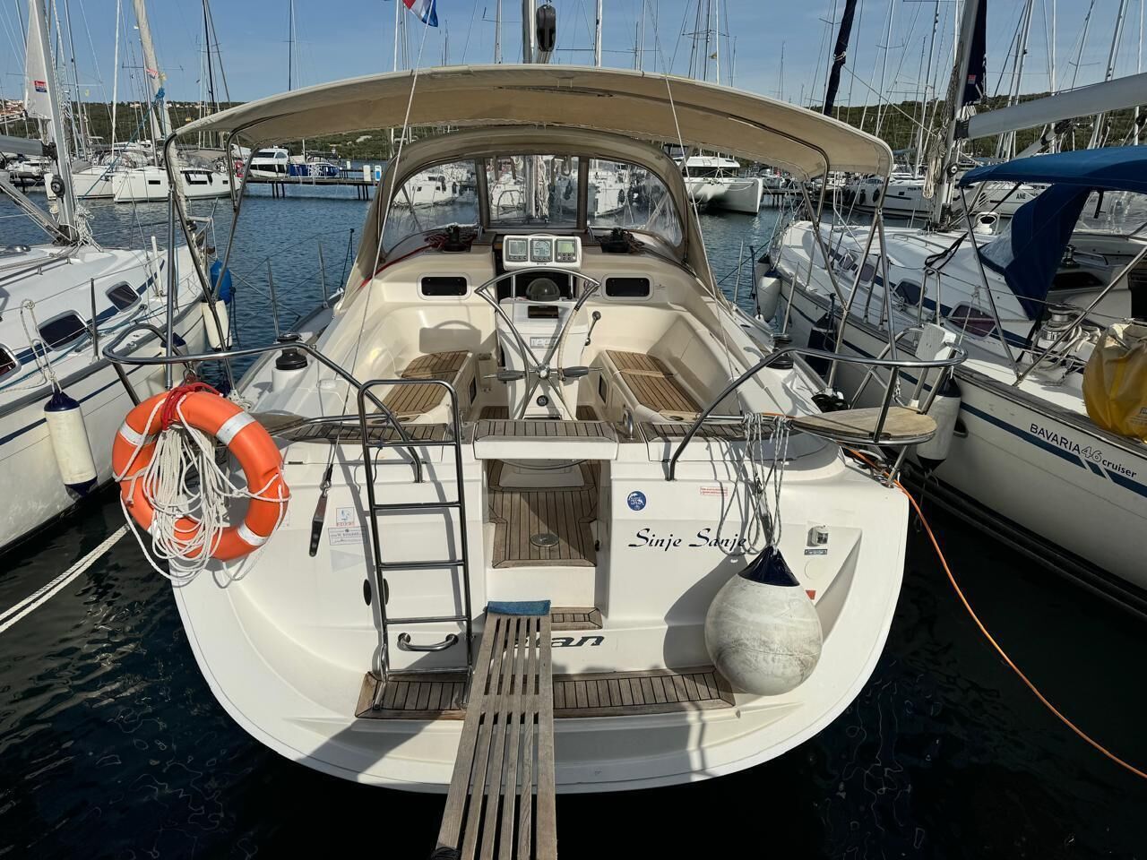 A boat docked at a marina with a steering wheel, life preserver, and a name 'Sinje Saij.'