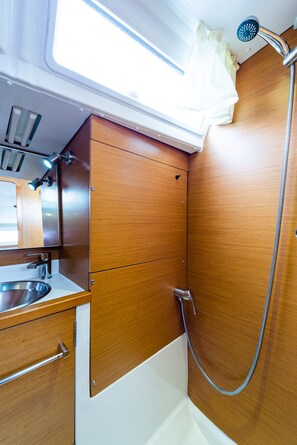 Ein kleines Badezimmer mit Dusche, Waschbecken und Spiegel.