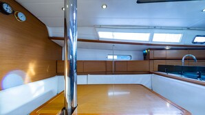 A boat's interior with a wooden table, white cushioned seating, a sink, and a window. - Sun-Kissed Sailing Adventure in the Ionian Islands, Lefkada (Lefkada)