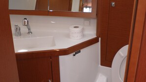 Casa de banho compacta com lavatório branco, sanita e espelho sobre o lavatório.