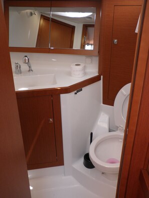 Ein kleines Badezimmer mit einem weißen Waschbecken, einer Toilette und einem Spiegel über dem Waschbecken.