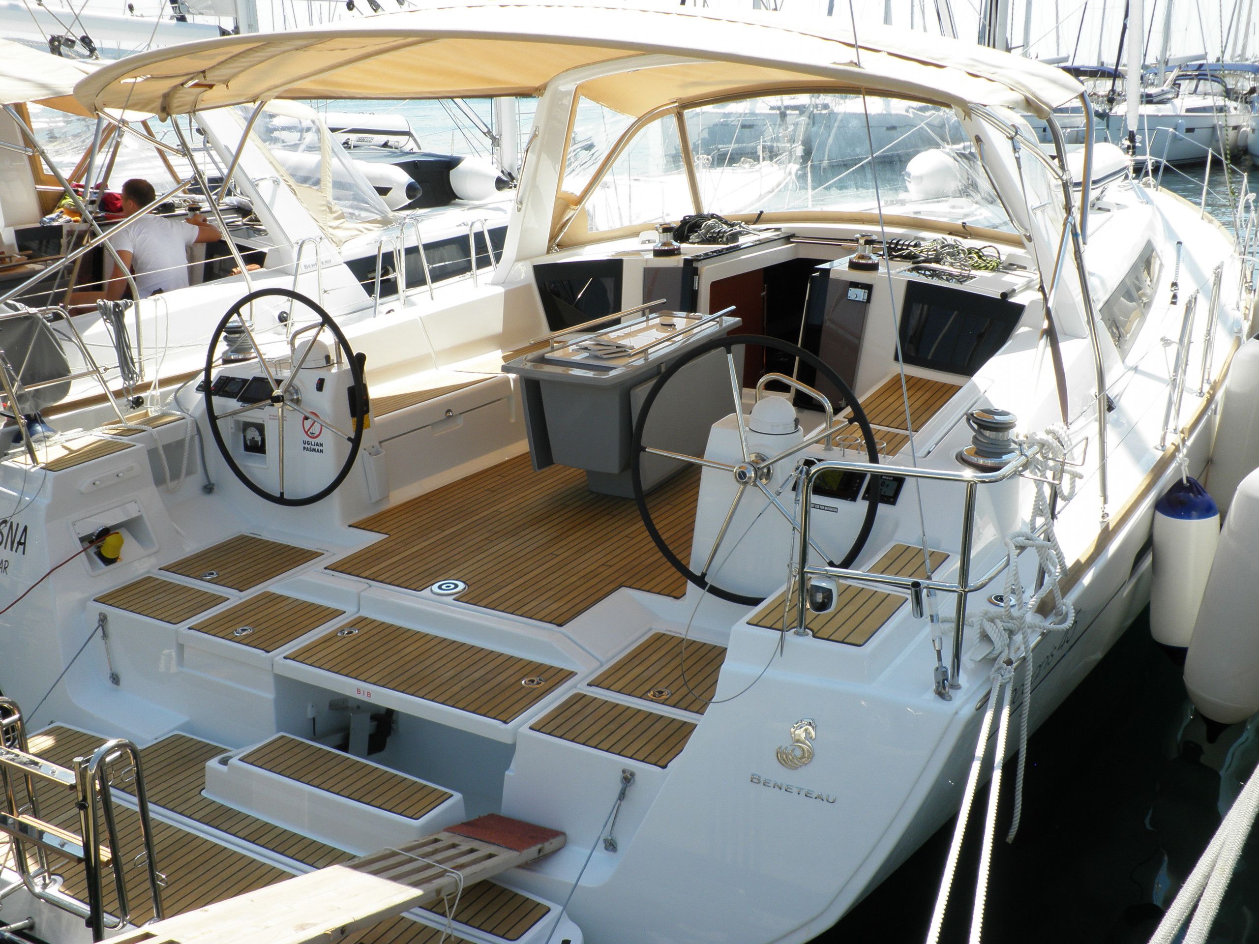 A yacht's deck with a steering wheel, control panel, and seating area.