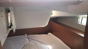 En kompakt säng med kuddar, en sänggavel, ett fönster och en kontrollpanel under sängen.
