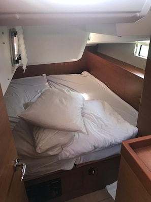 Ein kleines Bett mit Kissen, einem Kopfteil, einem Fenster und einer Bedienkonsole darunter.