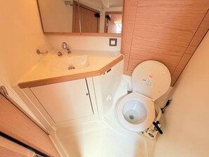 A compact bathroom with a white sink, a toilet, and a mirror. - Sun-Kissed Sailing Adventure in Zadar, Croatia (Bibinje)